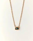 Aura Evil Eye necklace with a turquoise gemstone set in a gold plated pendant on a fine chain, styled as a luxury protective talisman.
