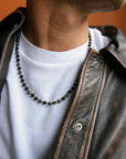 A man wearing the David Wrap in 18K Gold as a necklace, styled with a leather jacket for a modern, elevated look.