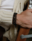 A man wearing the David Wrap in Black Rhodium as a bracelet, styled with a cream sweater and denim, showcasing the bracelet’s bold yet minimal look.