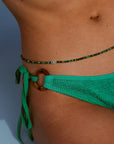 Model in green bikini wearing Juliana Belly Chain in Malachite Quartz with Evil Eye Charm at waist