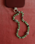 Natural jade Leah Phone Charm displayed in a heart-shaped form on a deep red background.