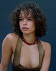 Model wearing the Lilou necklace in cherry quartz, showcasing the vibrant red beads and gold accents against the skin for a bold, statement look.