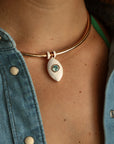 Close-up of the necklace worn with a denim top, showcasing the blue evil eye charm at the center of the collarbone.