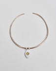 Gold collar necklace with a yellow ceramic evil eye charm and two white enamel dividers, displayed flat on a light background.