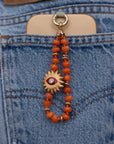 Clementine Quartz Mini India Phone Charm with Sun Evil Eye Charm clipped to phone in back pocket of blue denim jeans