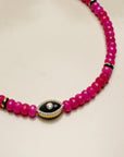 Close-up view of the Stella pink necklace highlighting the bright beads and the evil eye gold charm, a striking accessory for bold style statements.