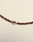 Close-up detail of the Julianna Garnet Necklace, showcasing the faceted beads and pavé evil eye charm centerpiece.