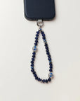 Overhead shot of the Sapphire Leah Phone Charm on a white background, featuring sapphire-toned beads and protective evil eye charms.