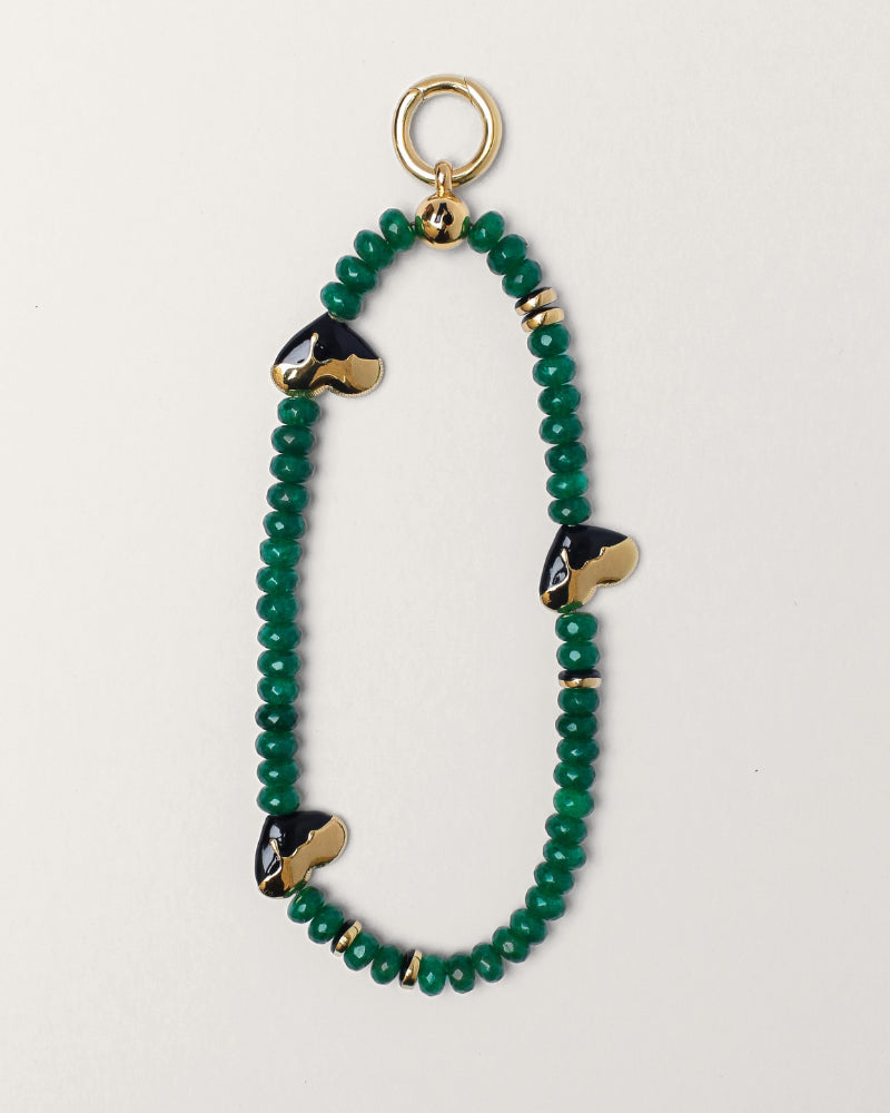 Aria wristlet in emerald quartz displayed in a flat-lay view, showcasing vibrant green beads and gold heart accents for a stylish statement piece.