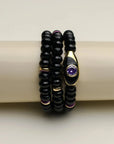 Stack of three Aya onyx quartz  bracelets with gold accents and purple details, displayed elegantly on a bracelet holder.