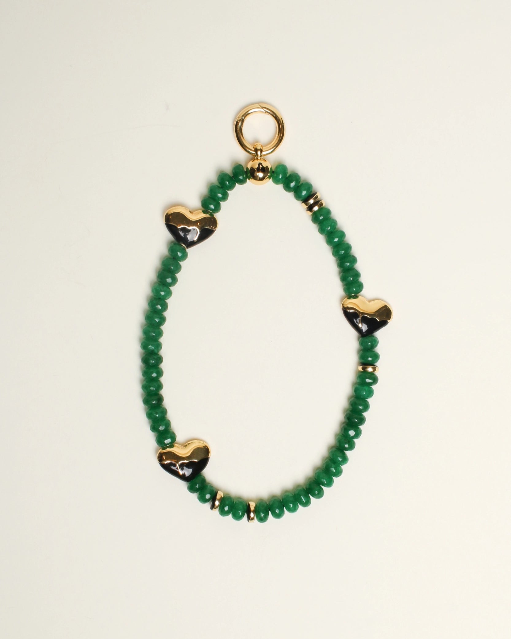 The Aria Bag Charm in Emerald displayed against a neutral background, showcasing its vibrant emerald quartz beads, 14k gold-plated heart charms, and refined craftsmanship for a chic and elegant design.