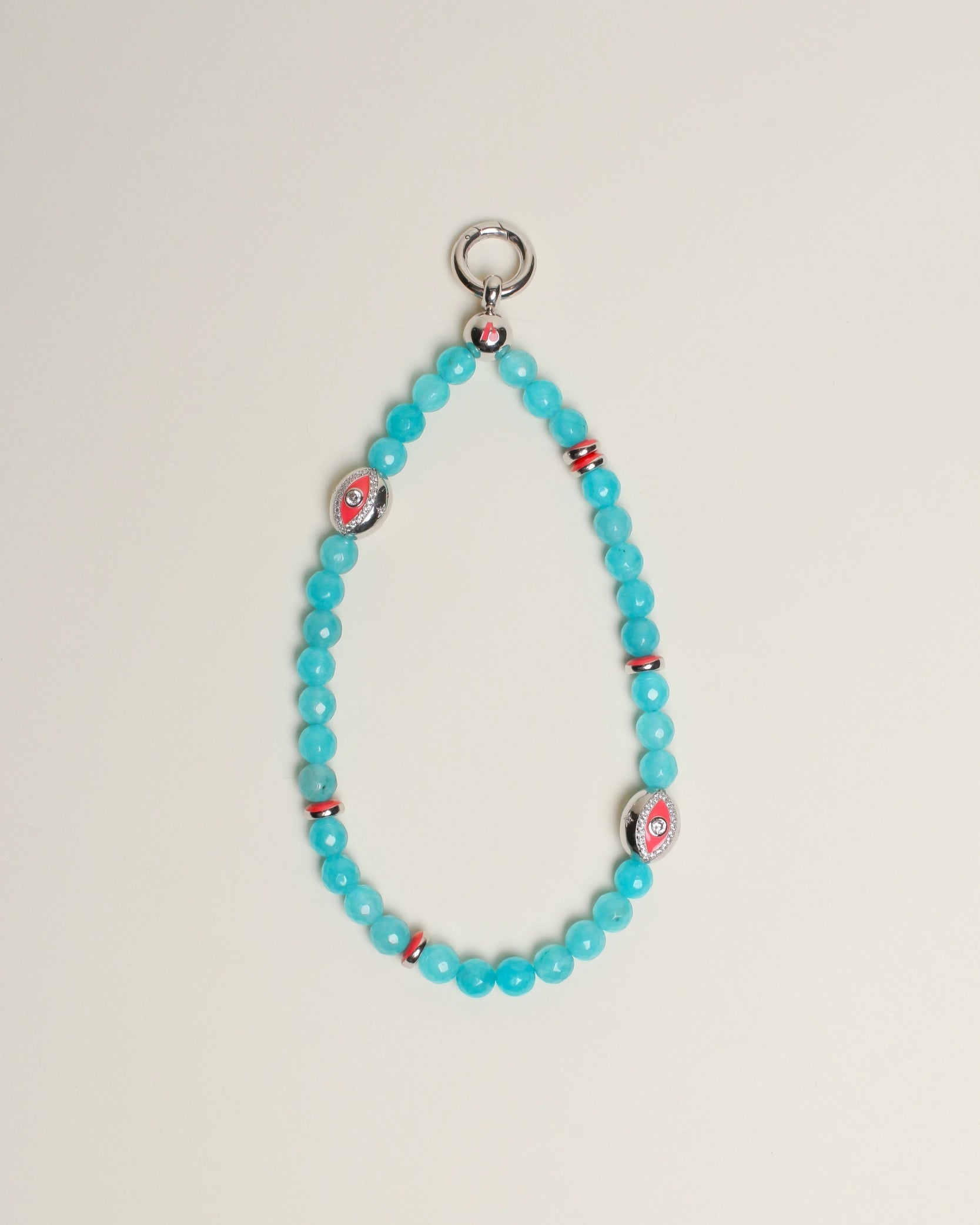 The Leah Bag Charm in Turquoise displayed against a neutral background, showcasing its faceted turquoise quartz beads, rhodium-plated silver Evil Eye charms, and pink accent dividers.