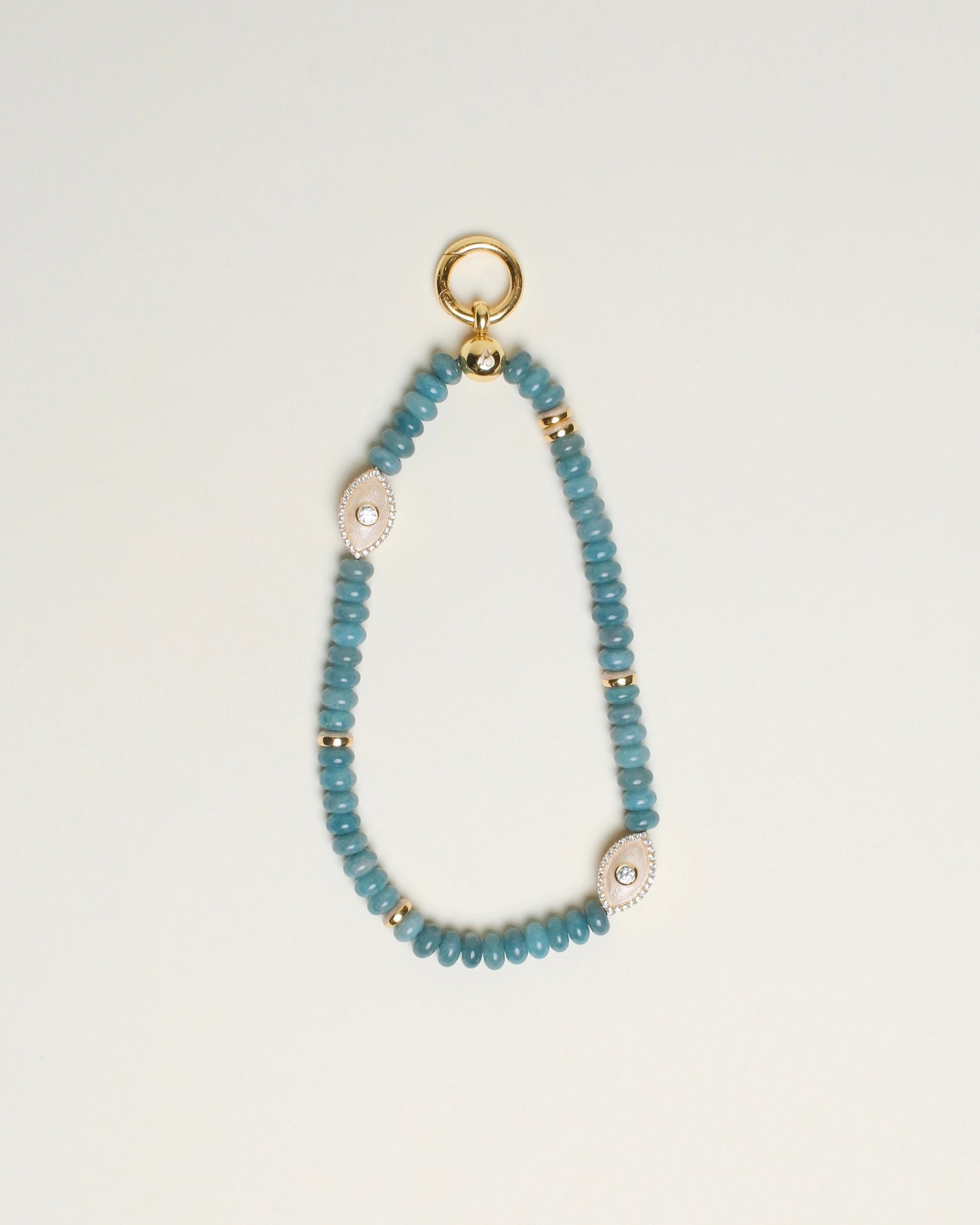 The Stella Bag Charm in Apatite, a luxe accessory handcrafted with semi-precious apatite quartz beads, 14k gold-plated accents, and a zirconia diamond Evil Eye charm, displayed on a neutral background.