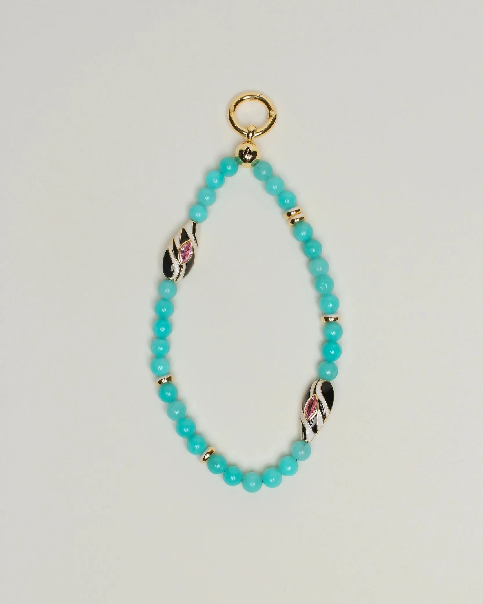 The Minou Bag Charm in Aqua displayed against a neutral background, showcasing its faceted aqua quartz beads, 14k gold-plated accents, and a striking Evil Eye charm.