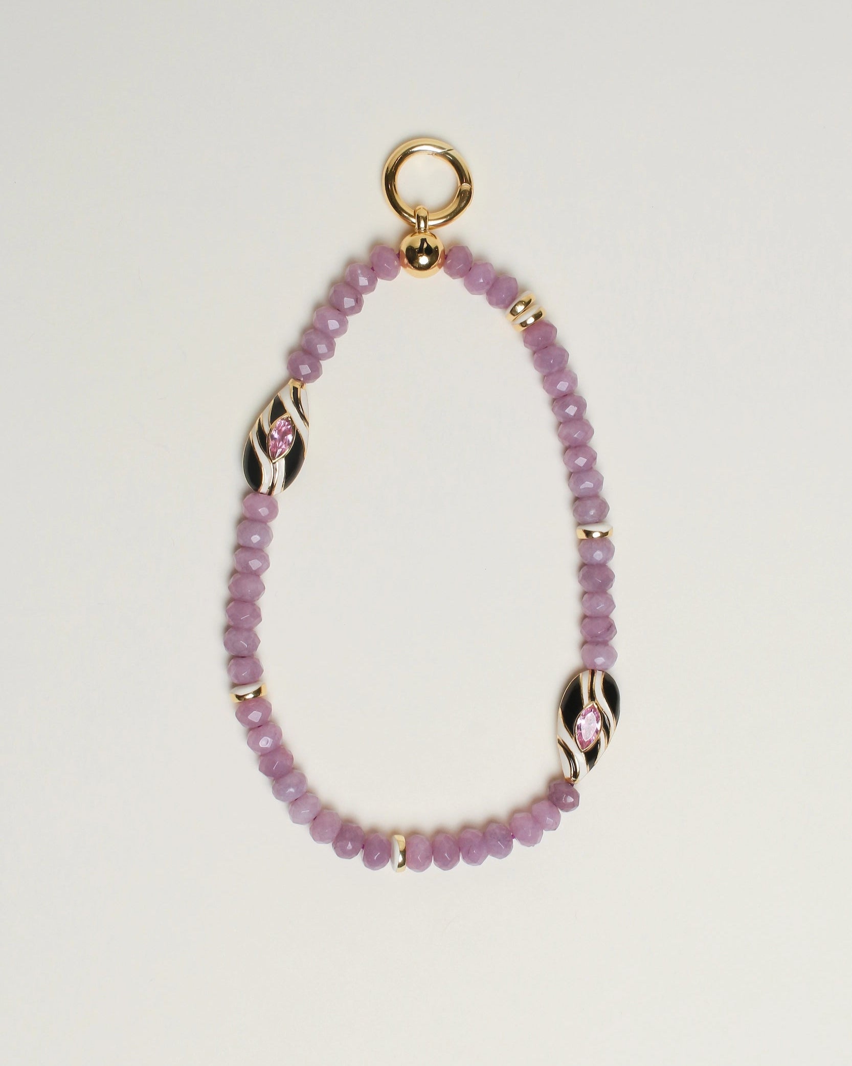 The Minou Bag Charm in Lavender displayed against a neutral background, showcasing its semi-precious lavender quartz beads, 14k gold-plated accents, and zebra-striped Evil Eye charm for a bold and meaningful design.