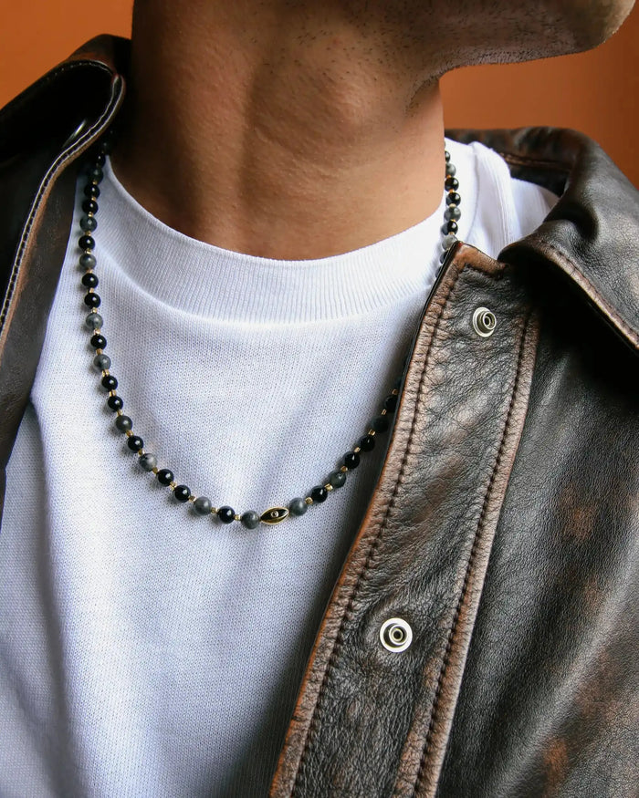 A man wearing the David Wrap in 18K Gold as a necklace, styled with a leather jacket for a modern, elevated look.