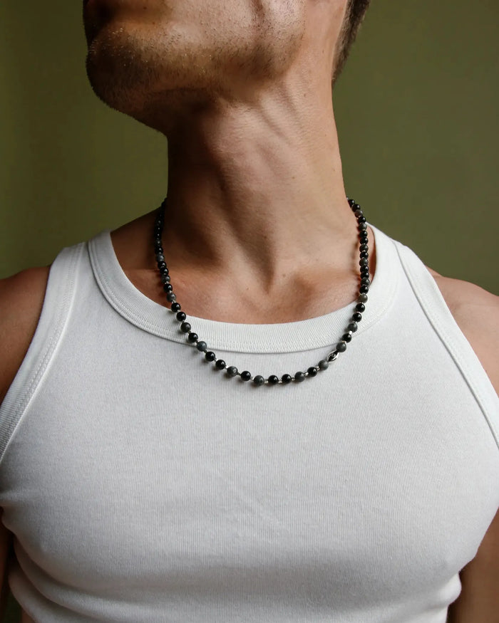 A man wearing the David Wrap in Silver as a necklace over a white tank top, highlighting the silver finish and dual evil eye charms with black CZ diamonds.