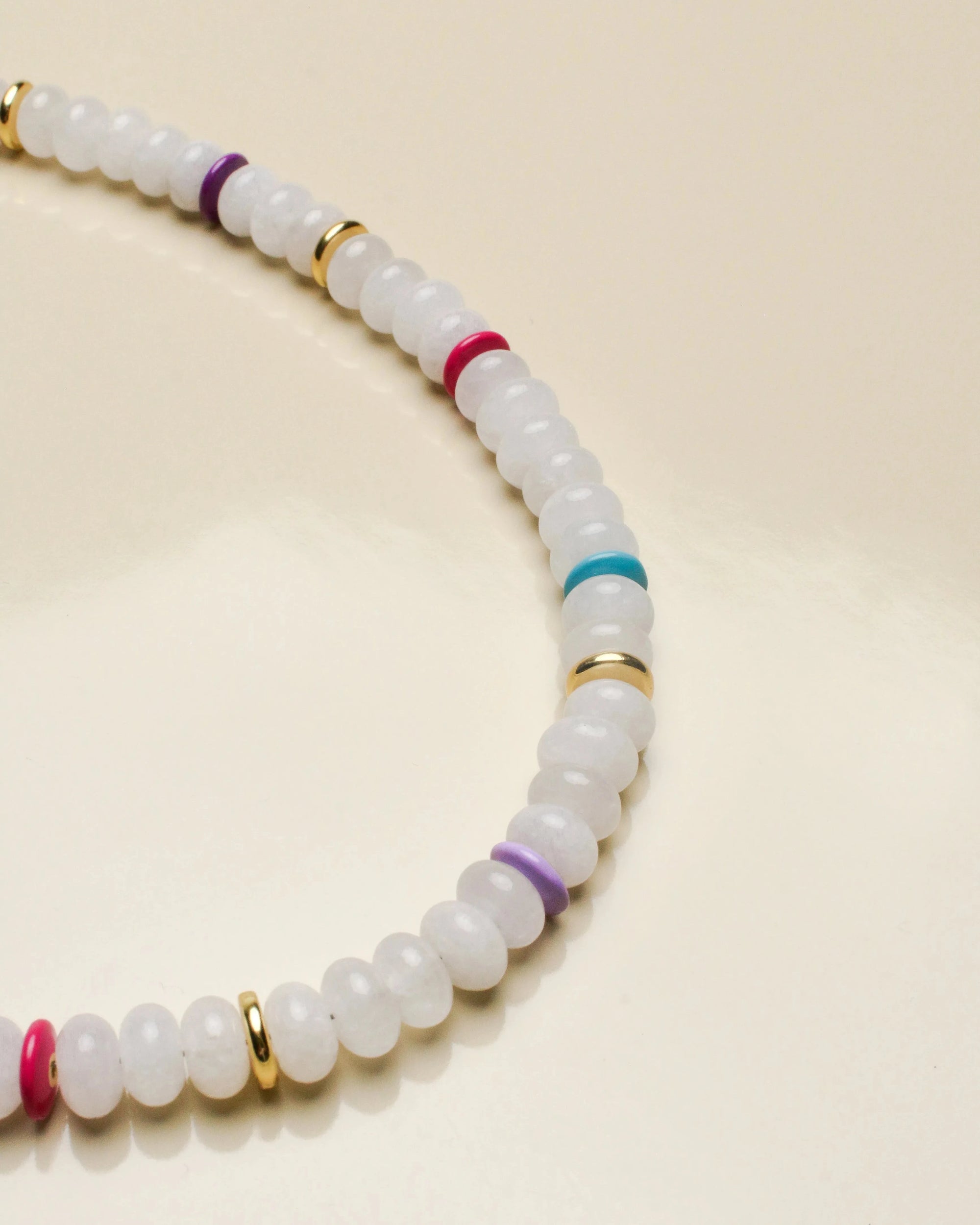 Close-up of the Ethan white quartz necklace highlighting its smooth white beads with pops of color from the multicolored and gold accent dividers.