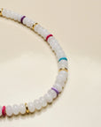 Close-up of the Ethan white quartz necklace highlighting its smooth white beads with pops of color from the multicolored and gold accent dividers.