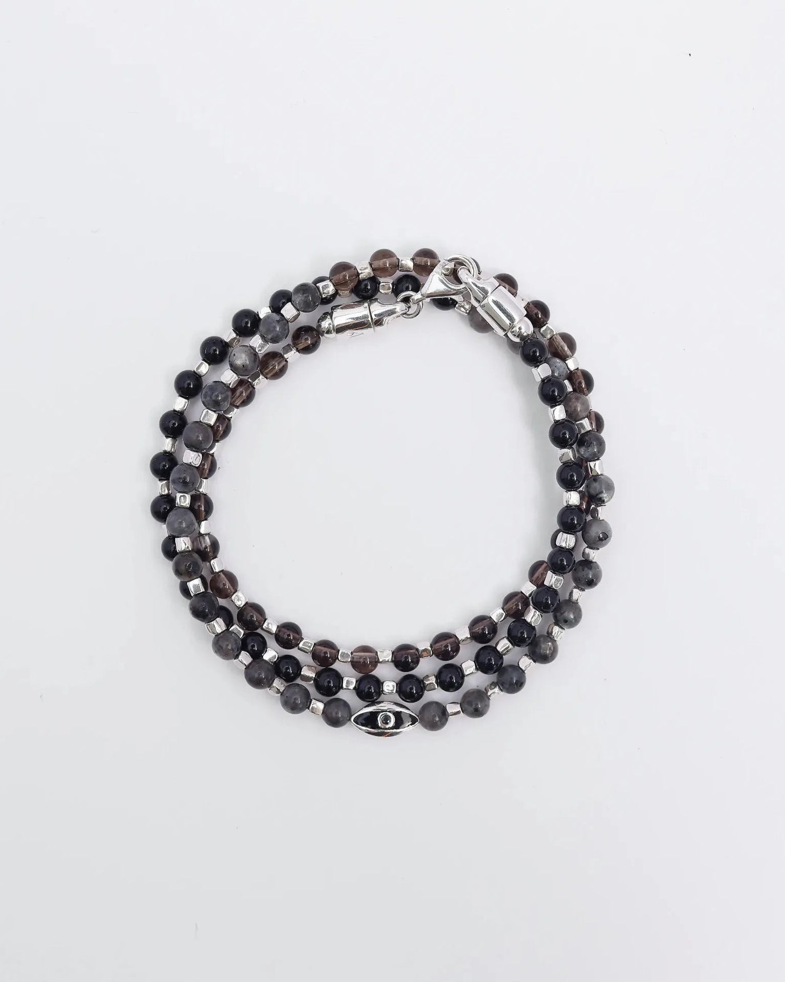 The Ethan Wrap in Silver laid flat and wrapped, showcasing its polished silver finish, 4mm black onyx, black labradorite, and smoky quartz beads, along with dual evil eye charms with black CZ diamonds.