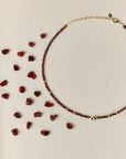 Garnet necklace with scattered gemstones on a beige background