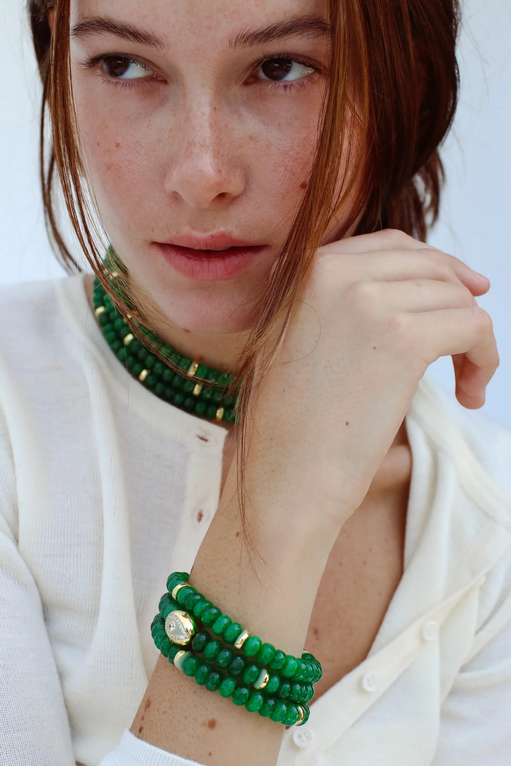 Model wearing the Leah Emerald Bracelet set, paired with a matching Lilou Emerald necklace. The bracelet stack showcases green quartz beads with gold accents, exuding a luxurious yet effortless look.