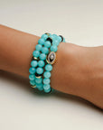 A set of three Leah aqua bracelets worn on the wrist, featuring soft blue beads with gold accents and a central eye charm for a chic and vibrant stack.