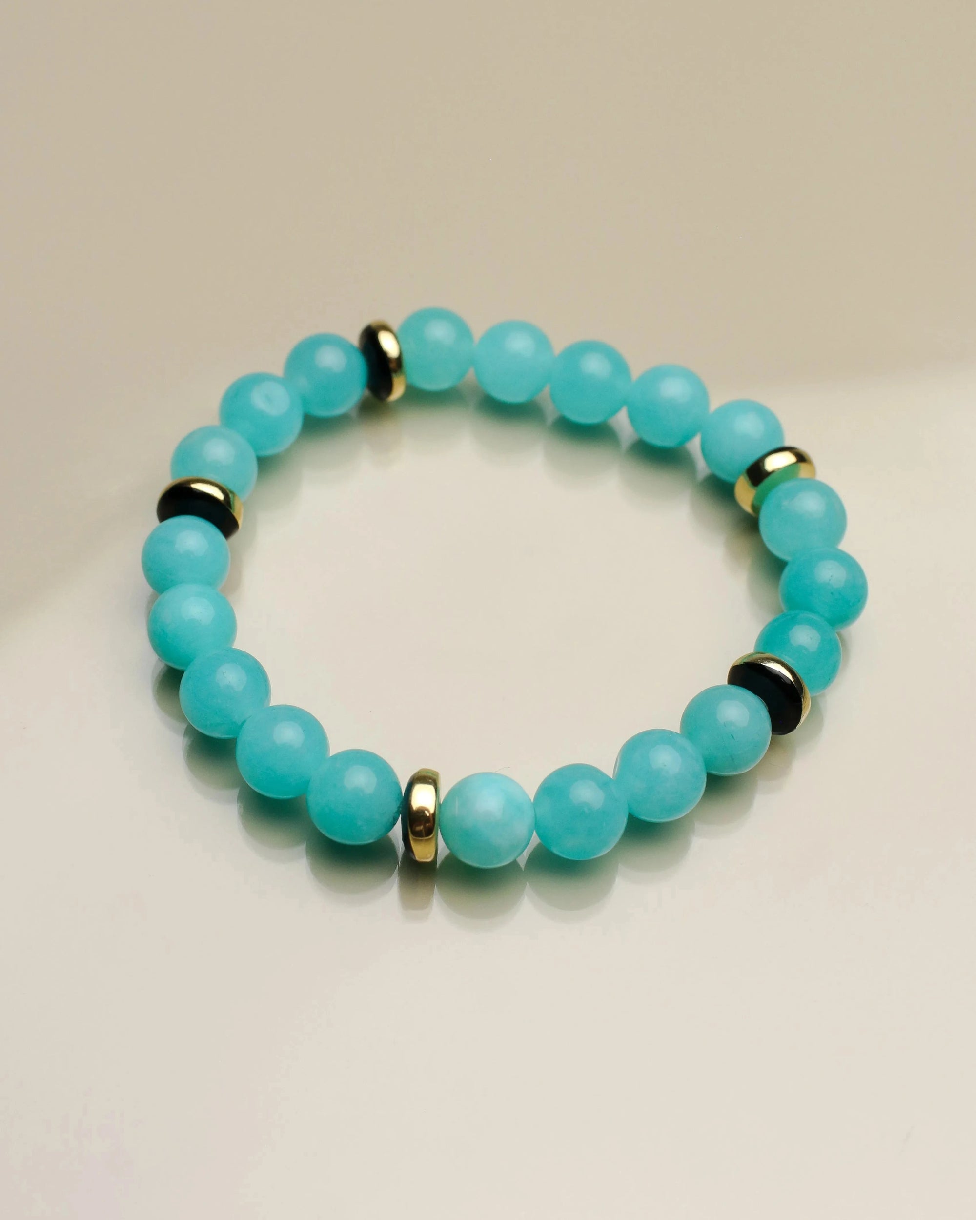 Another single Leah aqua bracelet shown flat, emphasizing its smooth blue beads, contrasting black dividers, and a striking central eye charm.