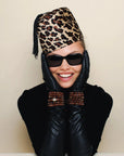 Stylish portrayal of a model wearing the Leah caramel bracelet stack over black leather gloves, paired with a leopard-print hat and sunglasses, highlighting a chic, bold look.