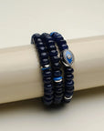 Leah sapphire quartz bracelets displayed on a cylindrical stand, highlighting the rich blue beads with silver accents and the eye-catching evil eye charm.