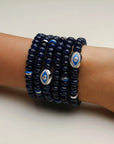Leah sapphire quartz bracelet six stacked on a wrist, showcasing the dark blue beads, silver detailing, and an elegant evil eye charm at the center.