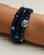 A set of three Leah sapphire quartz bracelets worn on the wrist, featuring deep blue beads with silver accents and a prominent evil eye charm for a striking layered look.