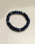 A single Leah sapphire quartz bracelet arranged flat, featuring deep blue beads accented with a central evil eye charm and silver dividers, symbolizing divinity and protection