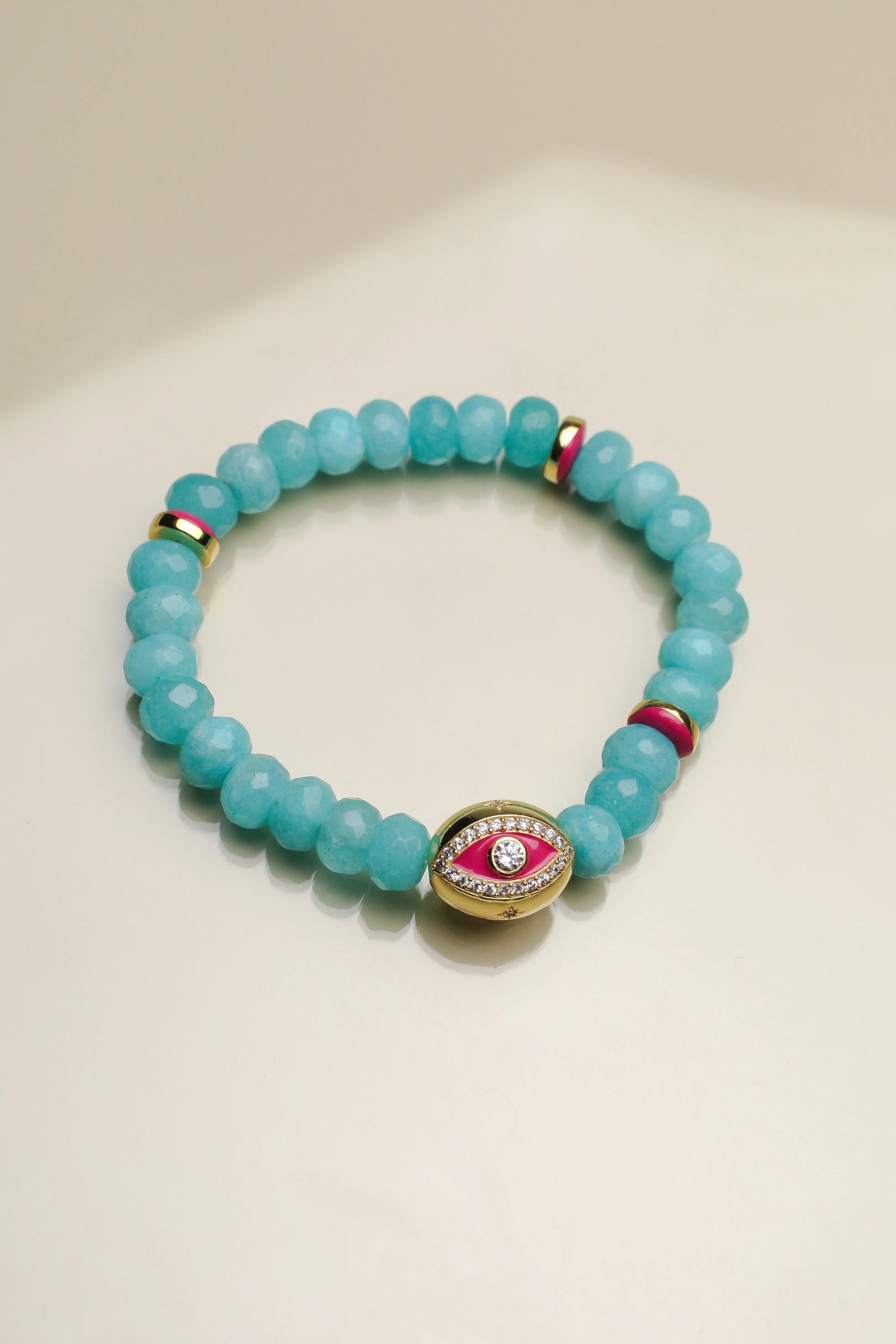 Close-up view of a single Leah turquoise bracelet, highlighting its striking blue-green beads, pink and gold accents, and a central eye charm.