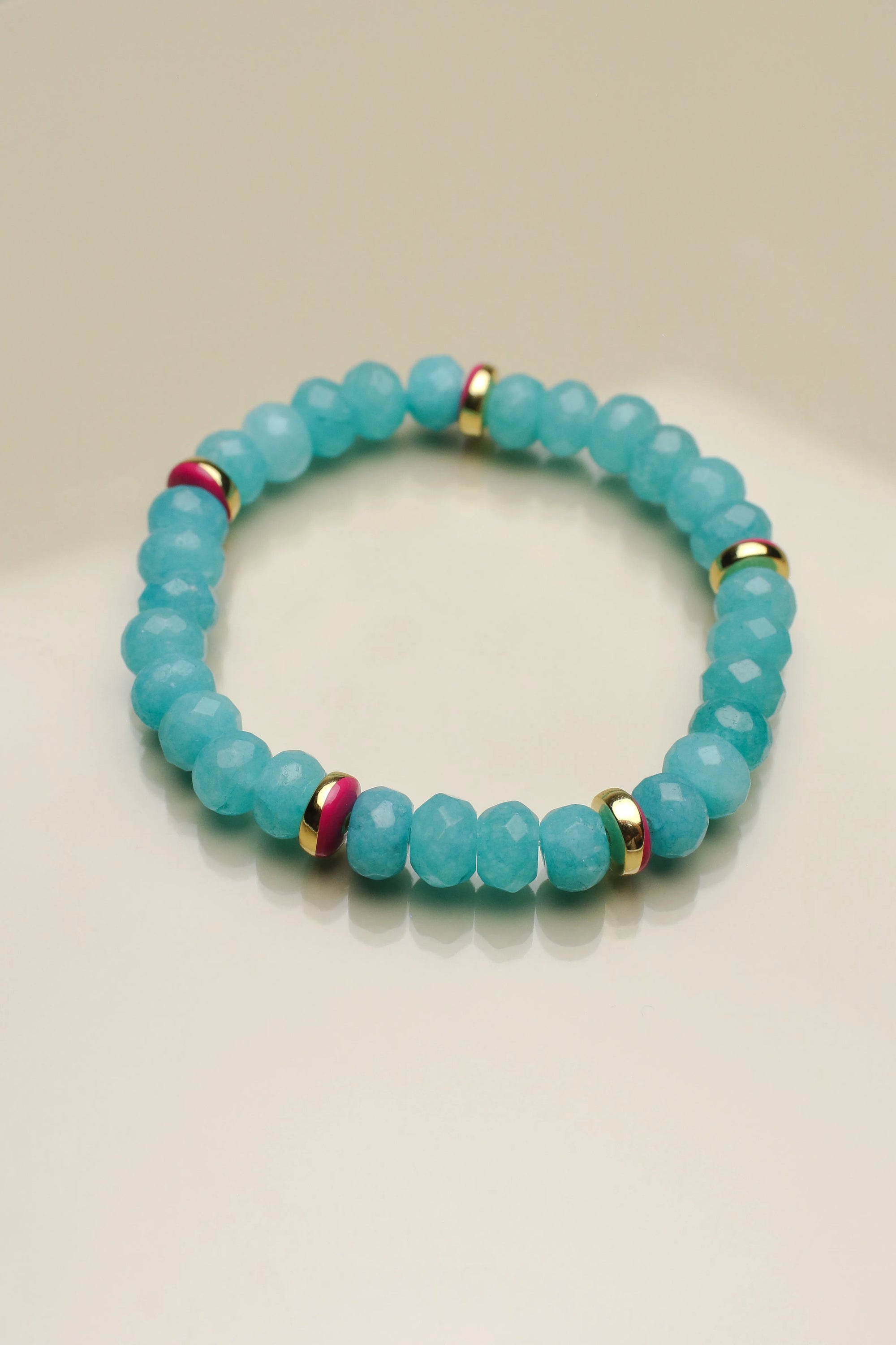 Single Leah turquoise bracelet arranged flat, emphasizing the turquoise beads with pink and gold dividers and a central eye charm for a unique, balanced design.