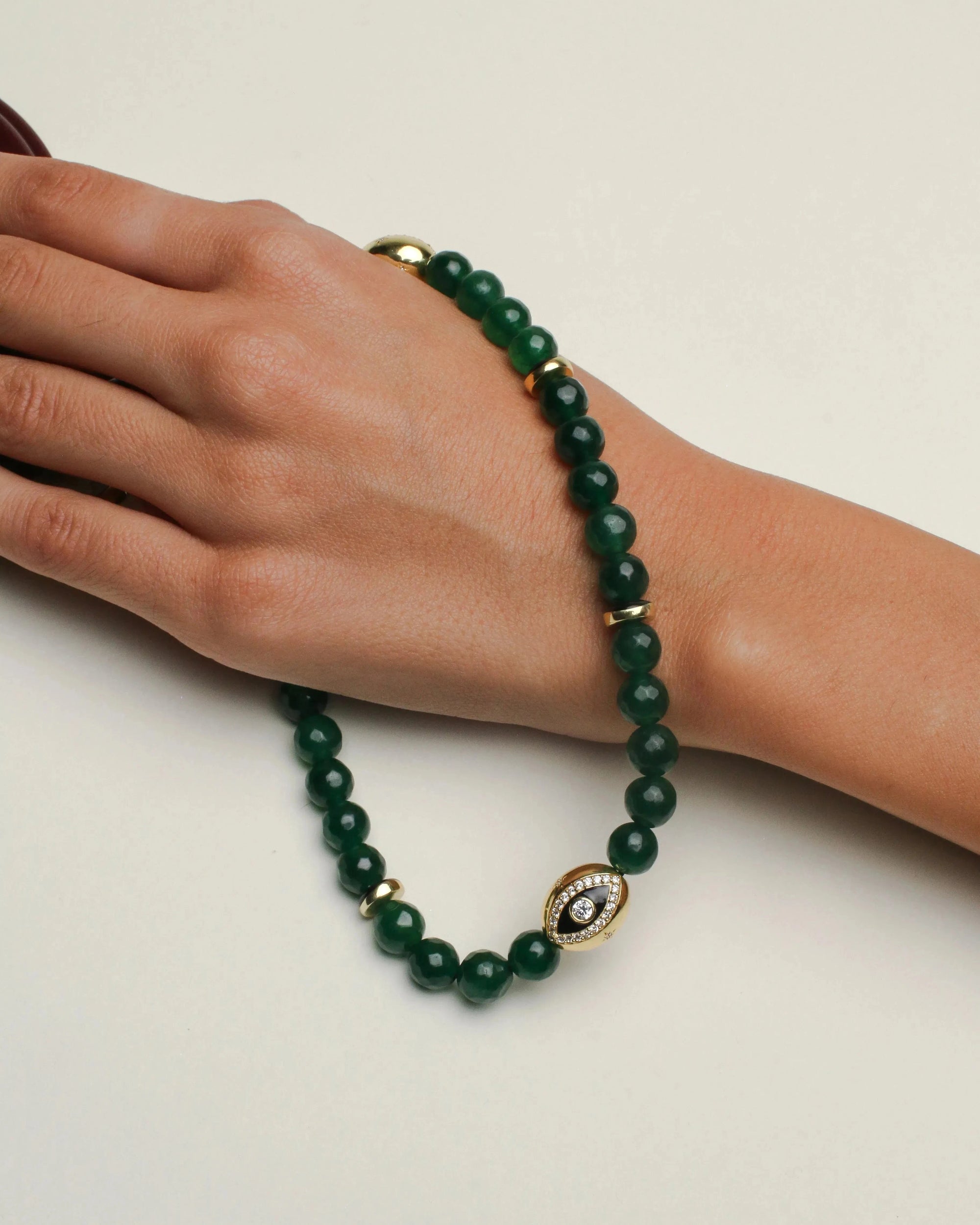 The Leah wristlet in emerald quartz worn on the wrist, featuring rich green beads with gold accents and a decorative charm, offering an elegant and luxurious look.