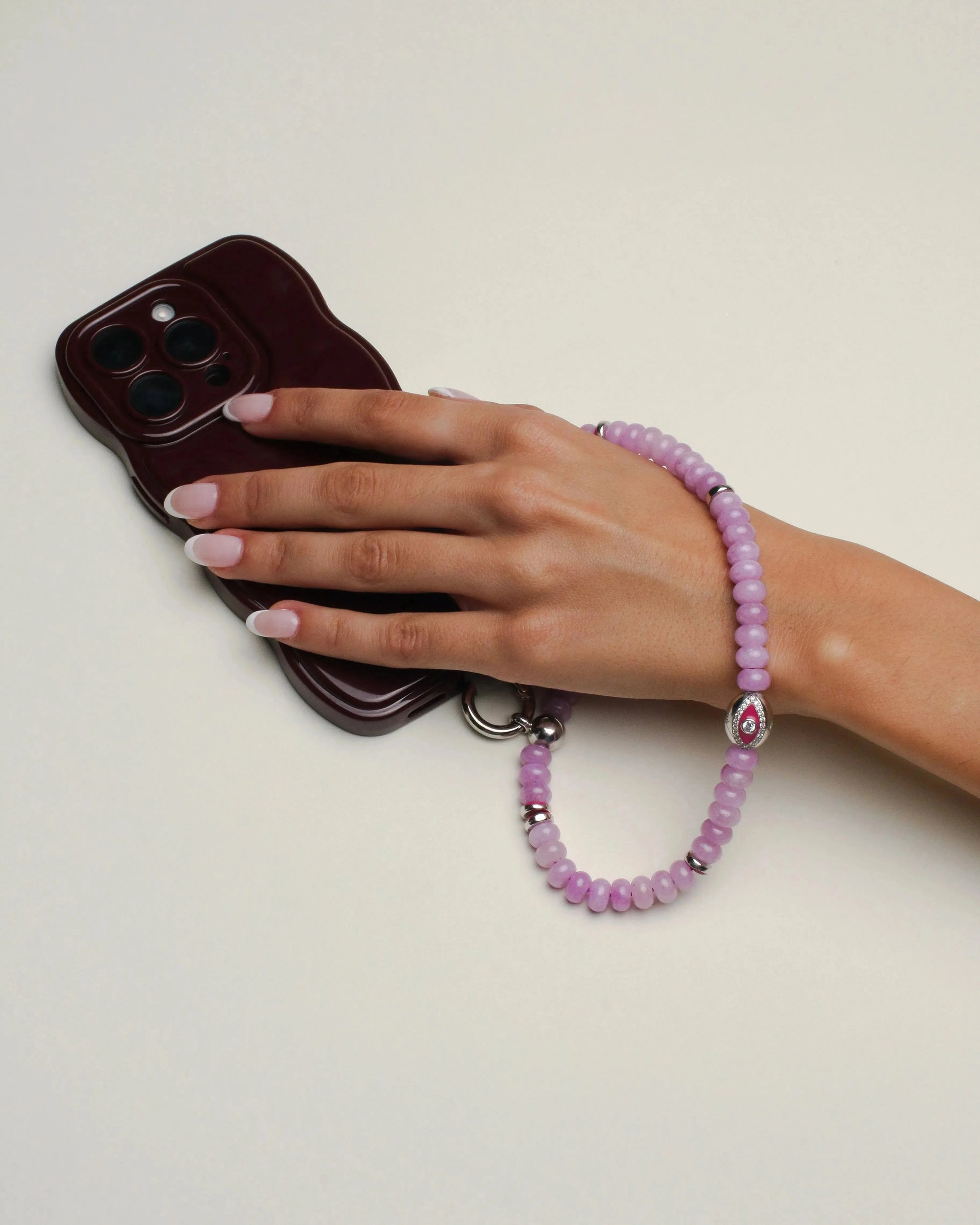 Close-up of the Leah wristlet in lavender quartz, attached to a phone case, highlighting its soft lavender beads, silver embellishments, and unique charm for versatile use.