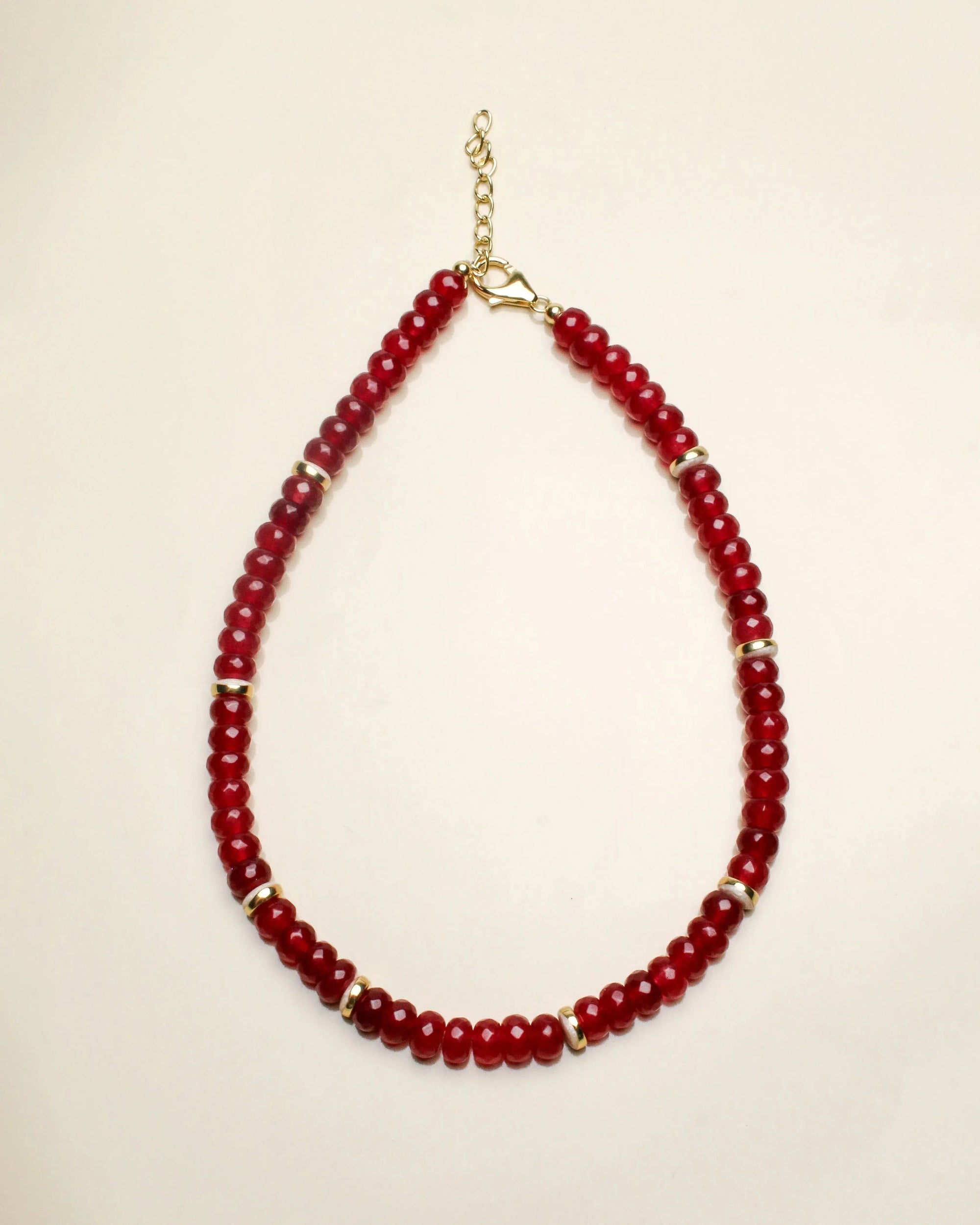 Lilou necklace in cherry quartz displayed flat, featuring deep red beads accented with gold dividers and a delicate chain clasp for a bold and elegant design.