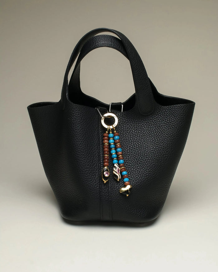 The Liora Bag Charm in Azure & Espresso styled on a sleek black tote bag, showcasing its versatility and chic design.