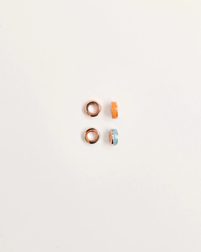 Set of four Lola Dividers featuring two gold-plated rings and two enamel rings in bold orange and cool blue, displayed on a white background.