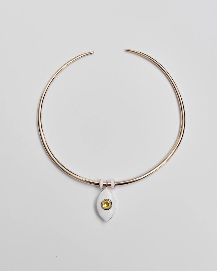 Gold collar necklace with a yellow ceramic evil eye charm and two white enamel dividers, displayed flat on a light background.