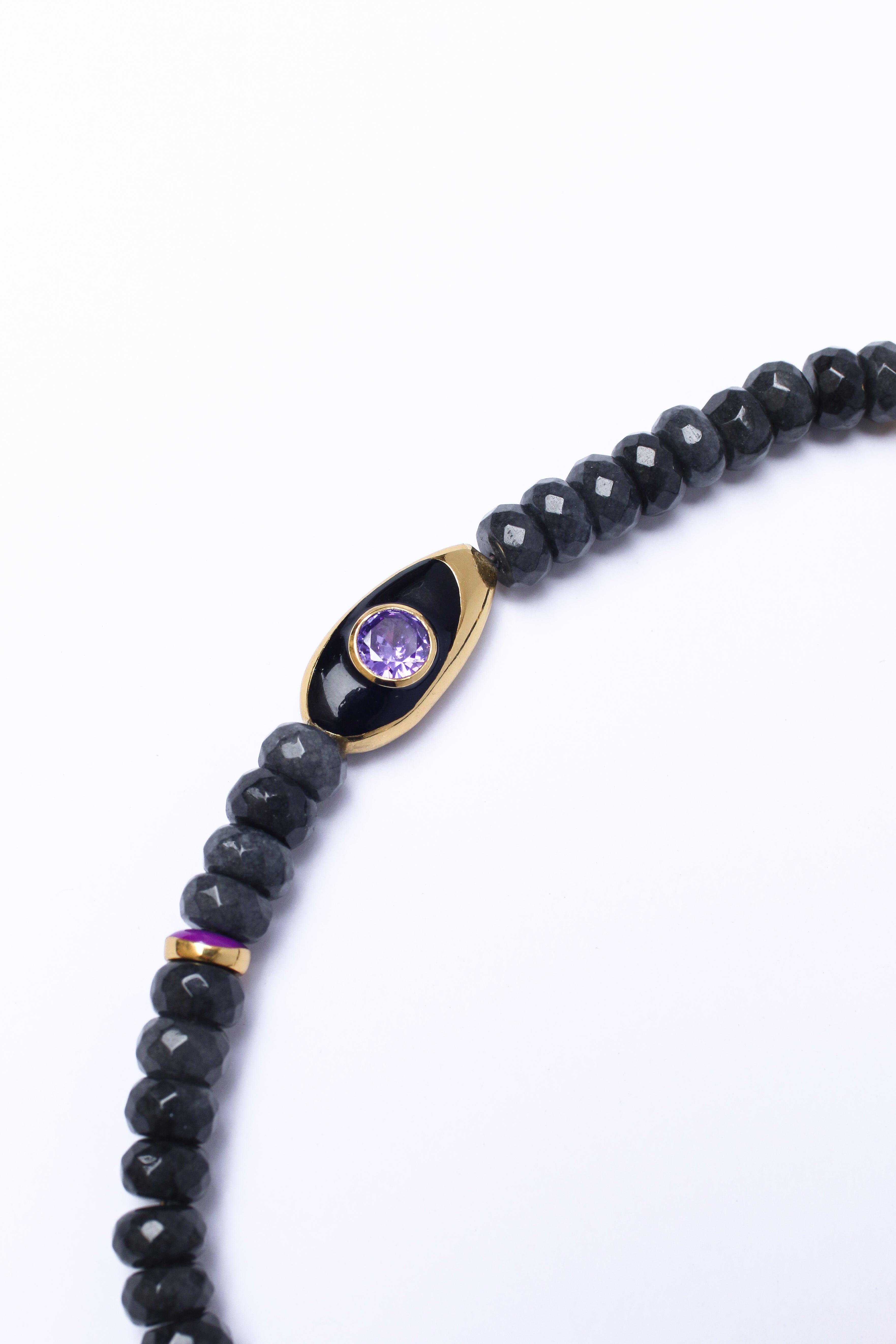 Black beaded phone strap, featuring an amethyst accent charm, on a white surface