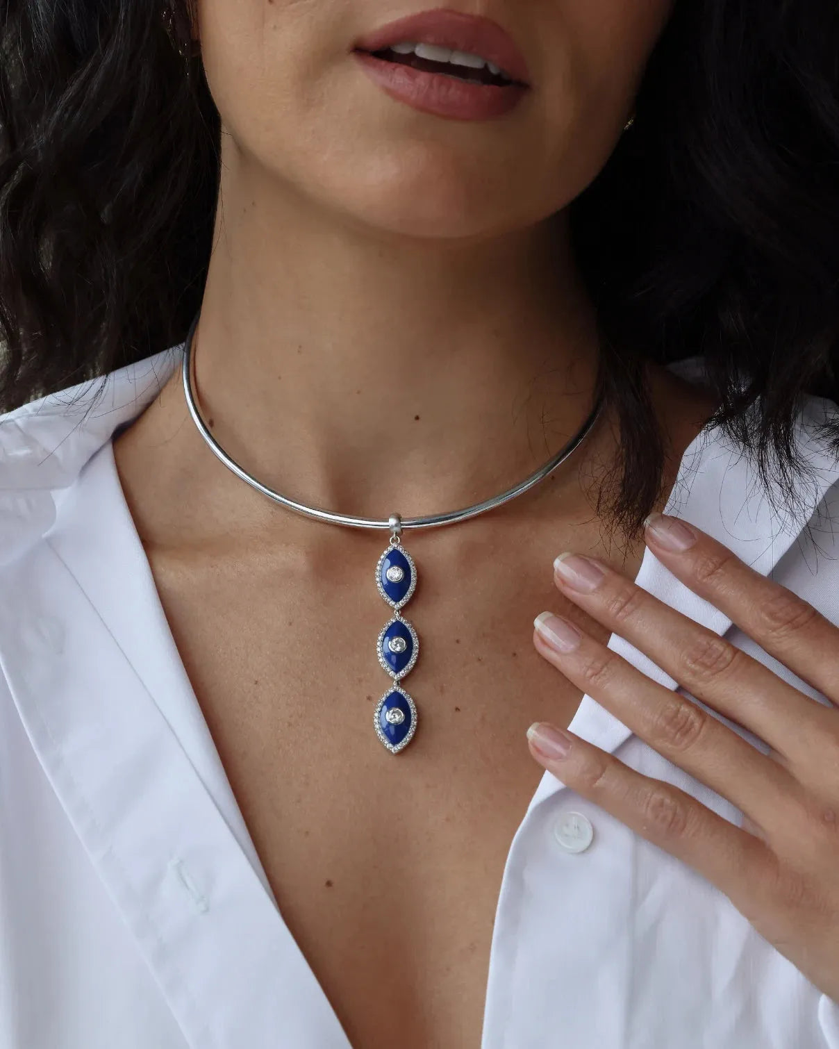 Woman wearing a silver choker necklace with blue evil eye pendants
