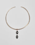 Gold collar necklace with two black enamel evil eye charms displayed flat against a white background.