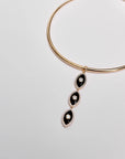 Close-up of the necklace laid flat, highlighting the trio of black enamel evil eye charms.