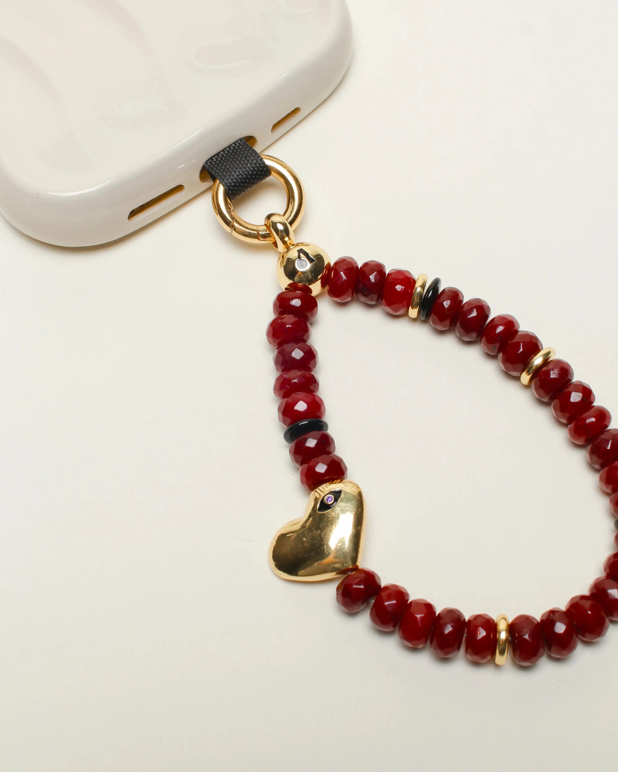 Mini Noelle Wristlet attached to a phone – The cherry quartz wristlet clipped to a phone, highlighting its versatility as a phone charm.