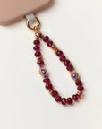 Mini Leah Ruby Quartz Phone Charm with evil eye beads and 14k gold accents attached to phone case.