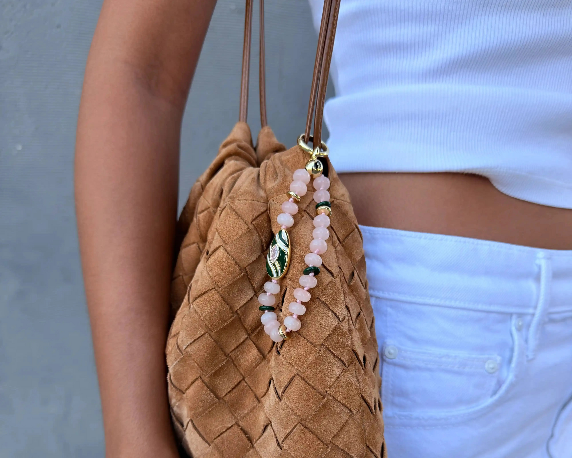 Mini Minou phone charm in rose quartz with soft pink gemstone beads and gold plated hardware styled on a phone.