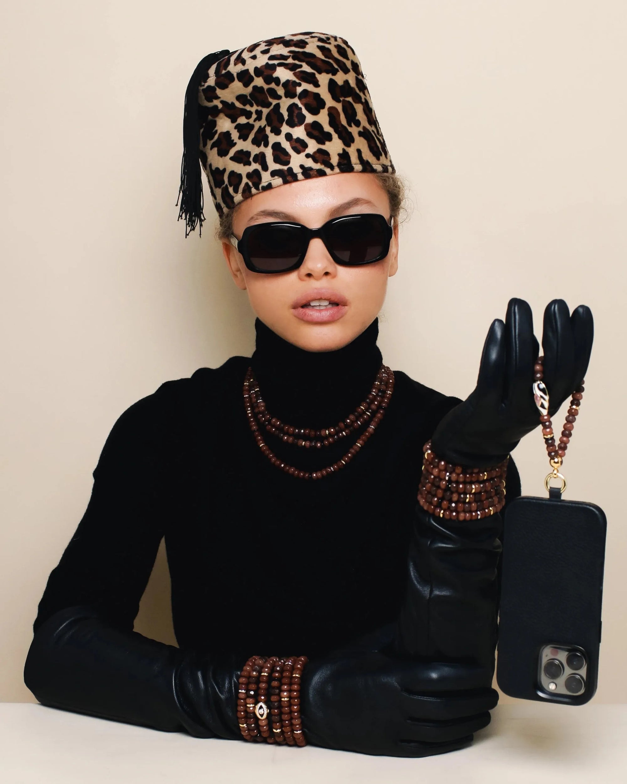 Model showcasing the Minou Mini Wristlet in Espresso, styled with leopard-print accessories and exuding confidence and flair.