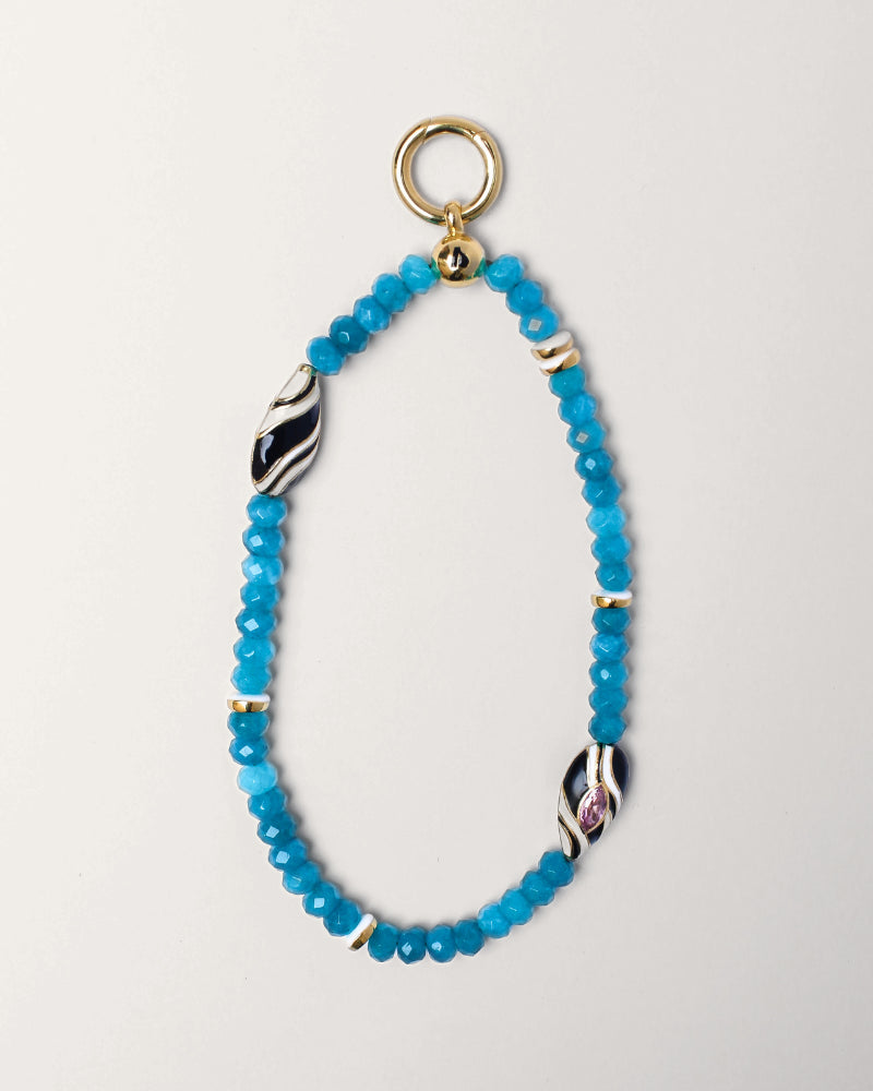 Full view of the Minou wristlet in turquoise quartz, featuring striking blue beads, gold accents, and a zebra-patterned evil eye charm, elegantly arranged.